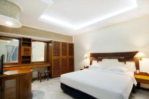 a bedroom with a bed and a desk and a television at Bali Bungalo Hotel in Kuta