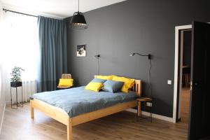 a bedroom with a bed with blue sheets and yellow pillows at Simple & Elegant Apartment in Liepāja