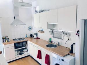 een keuken met witte kasten en een wastafel bij Light and Spacious Getaway House in Arnhem