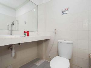 La salle de bains est pourvue de toilettes, d'un lavabo et d'un miroir. dans l'établissement RedDoorz @ Panglima Sudirman, à Surabaya