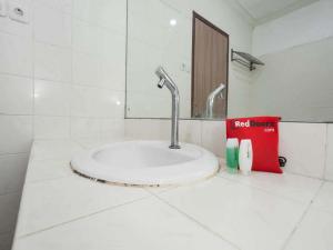 un baño con lavabo y un libro en una encimera en RedDoorz @ Panglima Sudirman, en Surabaya
