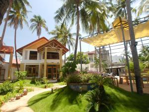 a house with palm trees in front of it at Coconut Garden Mui Ne in Mui Ne