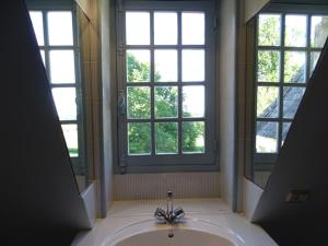 a bathroom with a sink and two windows at Château de la Redortière in Lézignac-Durand