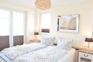 a white bedroom with two beds and two windows at Villa Ocean Time in Haffkrug