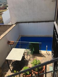 Un balcón con una mesa y una piscina azul. en Los Gañanes, en Puebla de Don Rodrigo