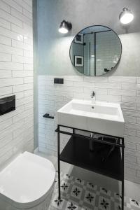 ein Badezimmer mit einem Waschbecken, einem WC und einem Spiegel in der Unterkunft Apartamenty przy Monte Cassino in Sopot