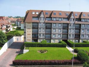um edifício de apartamentos com um jardim em frente em Lagrange Vacances Les Résidences em Villers-sur-Mer