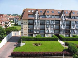 un immeuble d'appartements avec un jardin en face dans l'établissement Lagrange Vacances Les Résidences, à Villers-sur-Mer