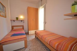two beds in a small room with a window at Ville Dogi Sud in Bibione