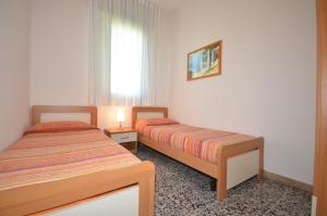 two beds in a small room with a window at Ville Dogi Sud in Bibione