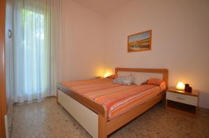 a bedroom with a bed with two lamps and a window at Ville Dogi Sud in Bibione
