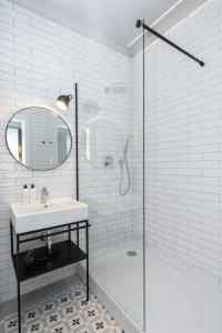 ein weißes Bad mit einem Waschbecken und einer Dusche in der Unterkunft Apartamenty przy Monte Cassino in Sopot