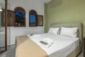 sypialnia z łóżkiem z białą pościelą i oknami w obiekcie Kiki Studios w Kalamákion
