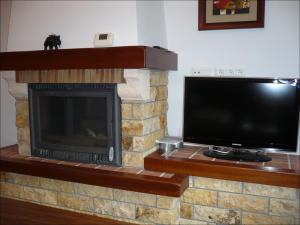 a tv and a fireplace with a television and a television at Casa MamaTere in Benamahoma