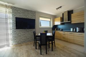 a kitchen with a table with chairs and a television on a brick wall at Apartamenty Piła in Piła