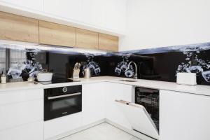 a white kitchen with black and white appliances at Apartments Warsaw Przyokopowa by Renters in Warsaw