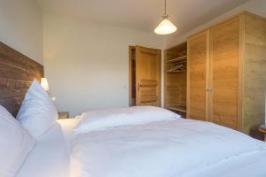 Schlafzimmer mit einem großen weißen Bett und Holzschränken in der Unterkunft Ferienwohnung Heigel in Oberstdorf