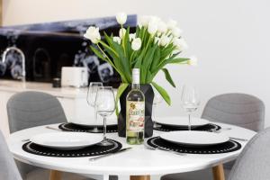 uma mesa branca com uma garrafa de vinho e flores brancas em Apartments Warsaw Przyokopowa by Renters em Varsóvia