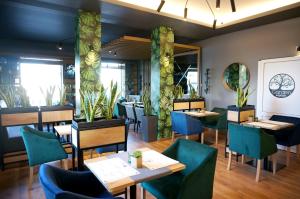 a dining room with tables and chairs and plants at Garden Zajazd in Rzeszów
