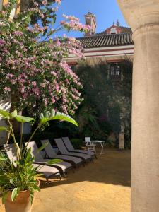 a group of chairs and a bush with pink flowers at Villa Elvira, exclusive Pool and Gardens in the heart of Sevilla in Seville