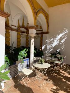 un patio con mesas y sillas en un edificio en Villa Elvira, exclusive Pool and Gardens in the heart of Sevilla, en Sevilla