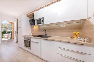 a kitchen with white cabinets and a sink at Apartments Santos in Vrsar