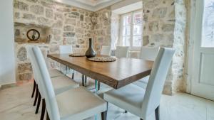 jadalnia z drewnianym stołem i białymi krzesłami w obiekcie Beachfront Villa Perast w mieście Perast