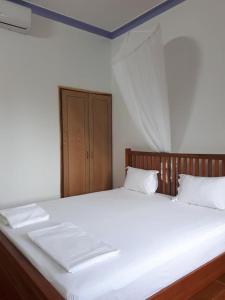 um quarto com uma cama grande com lençóis brancos e almofadas em Hiep Hoa Resort em Mui Ne