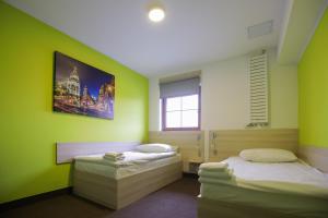 two beds in a room with green walls at Hotel Karczma u Macieja in Bolków
