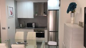 een keuken met witte kasten en een glazen tafel bij APARTAMENTO 128 ESPINEL in Ronda