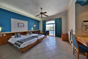 a bedroom with a large bed with a blue wall at Paradise Bay Resort in Mellieħa