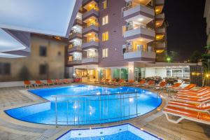 a pool in front of a hotel at night at Hawaii Suite Beach Hotel in Alanya