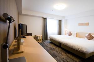a hotel room with a bed and a desk with a tv at Daiwa Roynet Hotel Osaka-Uehonmachi in Osaka