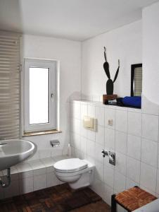 Baño blanco con aseo y lavamanos en Conny's Bistro und Pension en Rackwitz