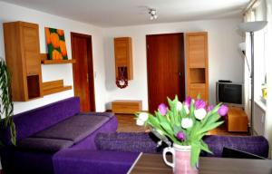 - un salon avec un canapé violet et une table fleurie dans l'établissement Conny's Bistro und Pension, à Rackwitz