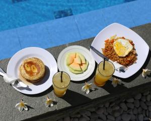 a table topped with plates of food and drinks at Kuri Garden Cottage in Nusa Penida