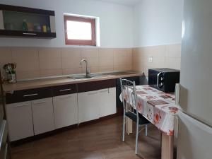 a kitchen with white cabinets and a sink and a table at Casa Dorgo in Lipova
