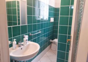 un bagno piastrellato verde con lavandino e servizi igienici di GALLURAS B&B a Olbia