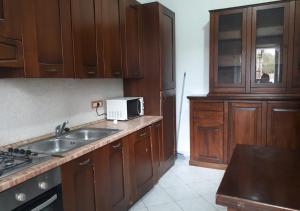 una cucina con armadi in legno, lavandino e forno a microonde di GALLURAS B&B a Olbia