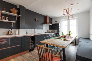 a kitchen with black cabinets and a wooden table at Courcy Road - 7 bedroom - sleeps up to 22 in London