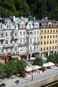 - un grand bâtiment blanc avec des tables et des chaises devant dans l'établissement Hotel Palacky, à Karlovy Vary