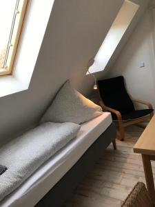 Bett in einem Zimmer mit einem Stuhl und einem Fenster in der Unterkunft Kleine Möwe in Neßmersiel