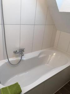 a white bath tub with a faucet in a bathroom at Kleine Möwe in Neßmersiel