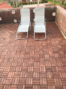 2 chaises blanches assises sur un patio en briques dans l'établissement Kleine Möwe, à Nessmersiel