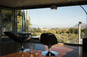 een kamer met een tafel en stoelen en een groot raam bij Country Villa Peloponnese with tennis court and pool in Zevgolateíon