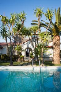 een huis met palmbomen en een zwembad bij Country Villa Peloponnese with tennis court and pool in Zevgolateíon