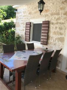 a dining room table with chairs and a stone wall at Dalmatinska kuća Terace in Skradin