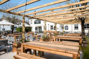 a wooden pergola with wooden tables and chairs at Rashleigh Arms in St Austell