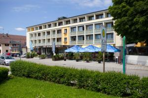 ein großes Gebäude mit blauen Sonnenschirmen davor in der Unterkunft Hotel Mayer in Germering