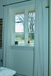 ventana en un dormitorio con cortina blanca en Grastenhus Guesthouse en Thurø By